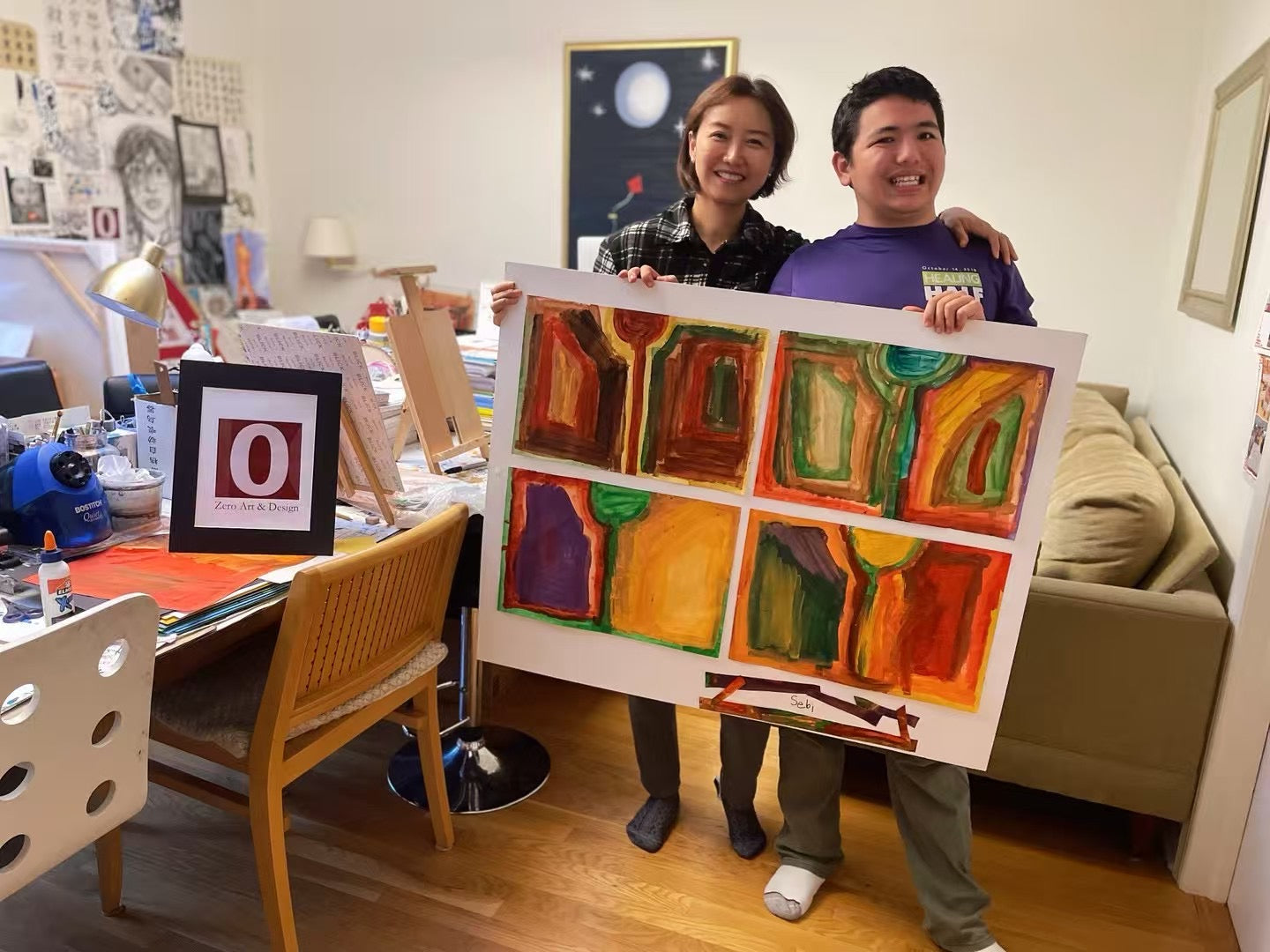 Sebastian Kravitz holding large painting with mentor